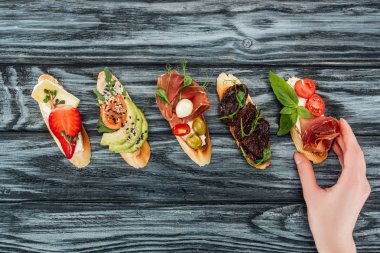 kadın ve jambon, somon ve sebzeler ile İtalyan bruschetta görünümünü ahşap masa üzerinde kırpılmış