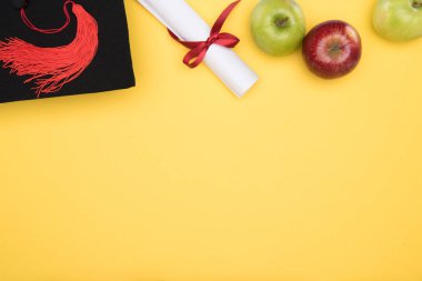 Sarı yüzeyi akademik kap, diploma ve elma Üstten Görünüm