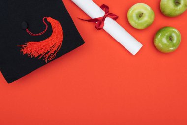 Kırmızı yüzeyi akademik kap, diploma ve elma Üstten Görünüm
