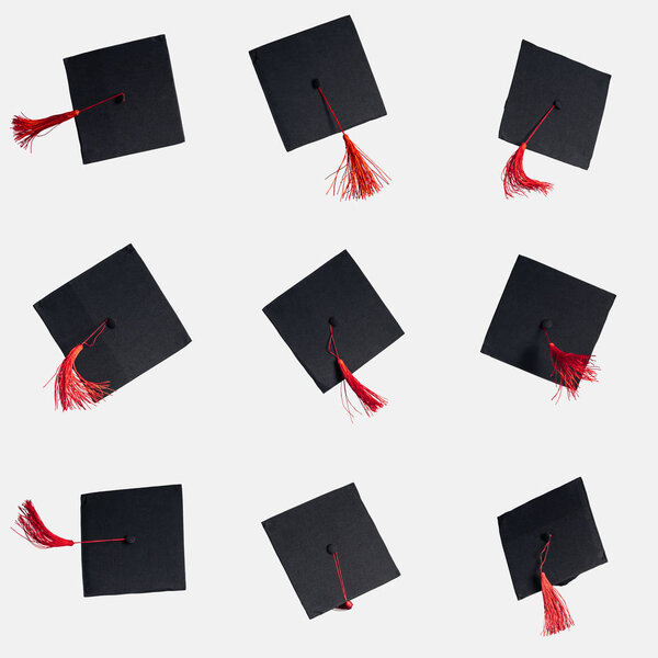 Black academic caps with red tassels isolated on white