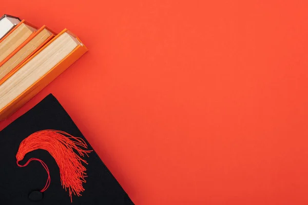 真っ赤な表面上の書籍と学術キャップ トップ表示 — ストック写真