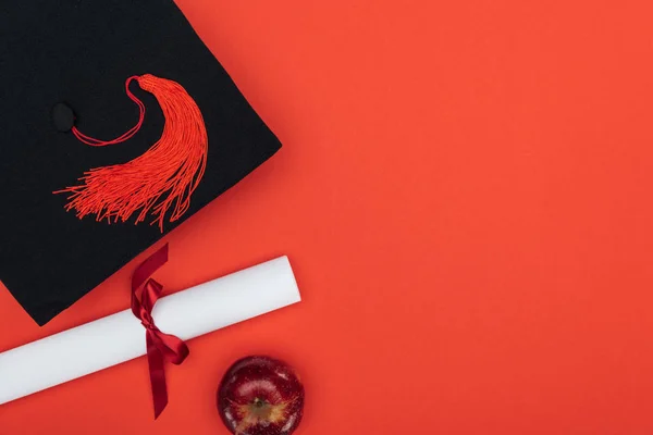 真っ赤な表面に学術キャップ 卒業証書とアップルのトップ ビュー — ストック写真