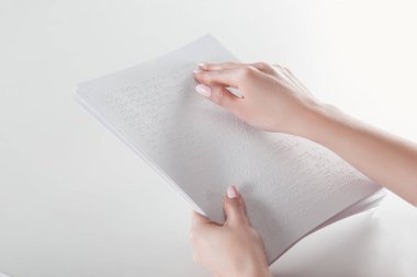 cropped view of young woman reading braille text with hand on white paper clipart
