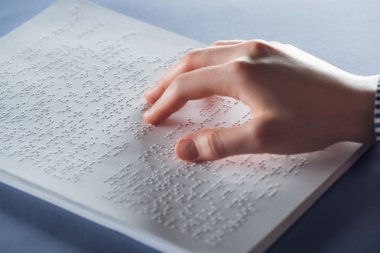 close up view of young woman reading braille text with hand