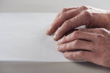 partial view of senior man reading braille text isolated on grey clipart