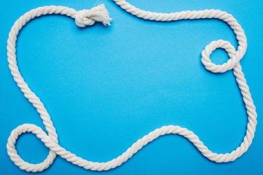 top view of white waved long rope with knot isolated on blue clipart
