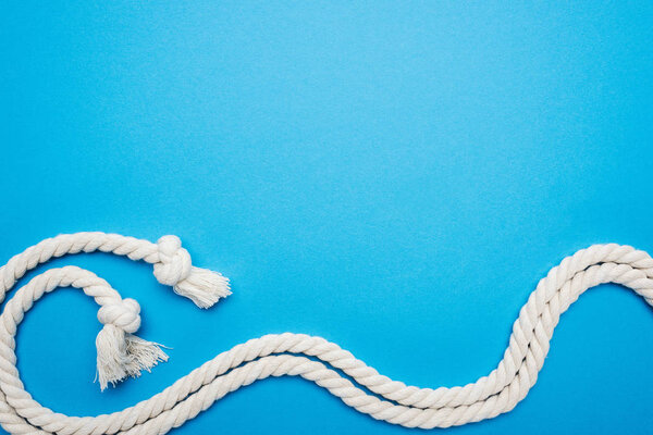 white long waved ropes with knots isolated on blue