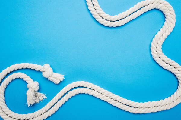 long white waved ropes with knots isolated on blue