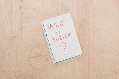 top view of what is autism question written in notebook on wooden table clipart