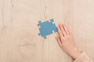 Mavi bulmacalar yakınındaki el görünümünü ahşap masa üzerinde kırpılmış