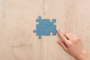 ahşap masa mavi puzzle parçaları, parmakla işaret eden el kırpılmış görünümünü bağlı