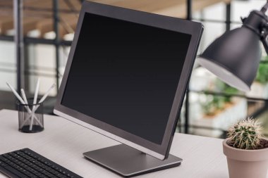 selective focus of computer with blank screen at workplace in office clipart