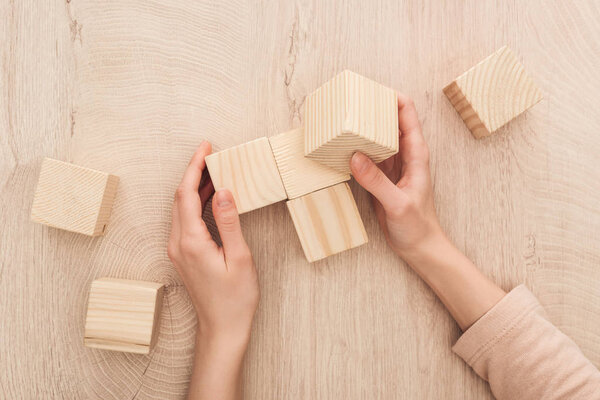 partial view of female hands near blank wooden cubes