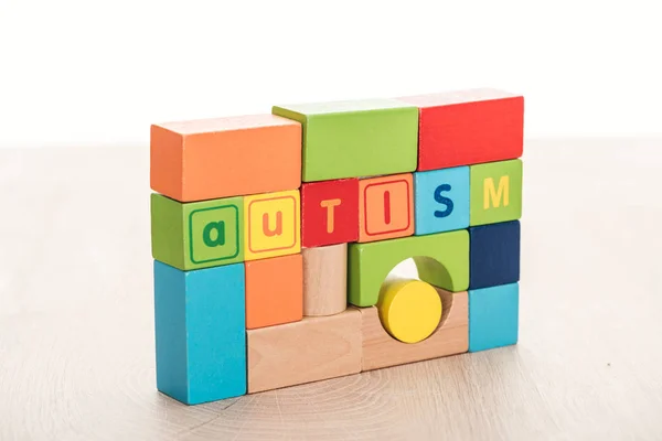 autism lettering made of multicolored building blocks on wooden surface isolated on white