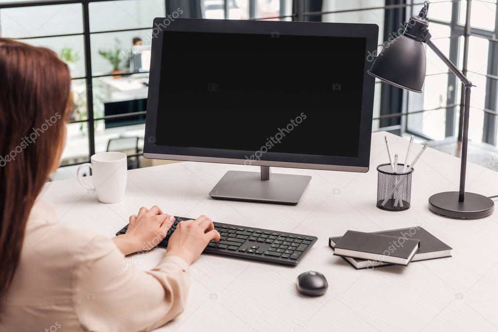 selective focus of woman using computer at workplace in office