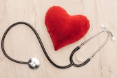 top view of bright toy heart and stethoscope on wooden background 