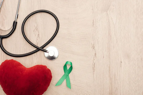 在木制背景上的玩具心脏 听诊器和绿色丝带的顶部视图 — 图库照片