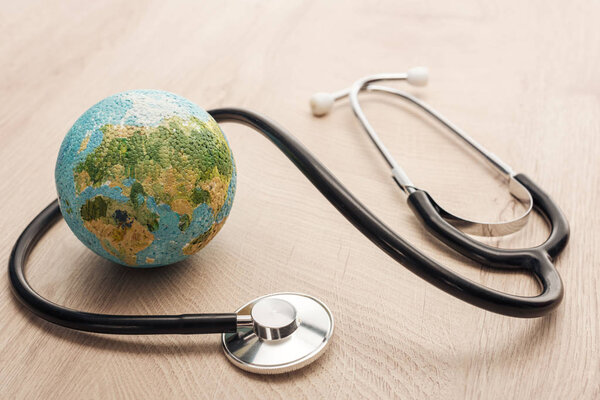 selective focus of stethoscope and toy earth on wooden and white table 