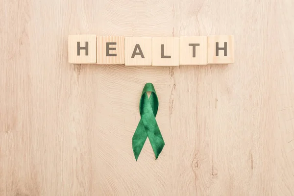 在木制背景上带有健康字母和绿色丝带的立方体的顶部视图 — 图库照片