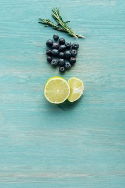 Mavi dokulu yüzeyde kesme limon, yaban mersini ve biberiye üst görünümü