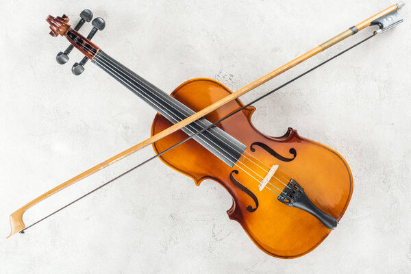 верхний вид классической виолончели с луком на сером фоне
 