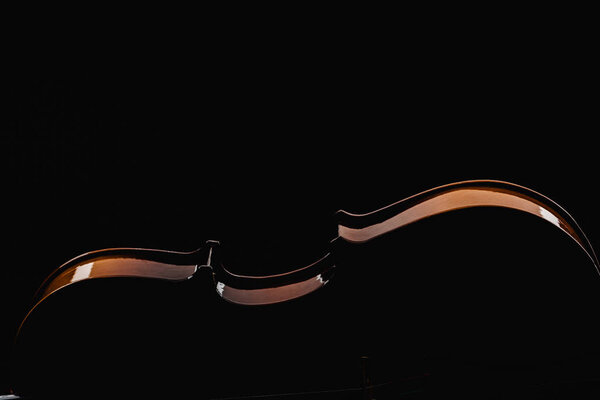 close up of wooden violoncello in darkness isolated on black