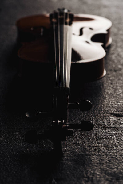 закрытие струн на виолончели в темноте на сером фактурном фоне
