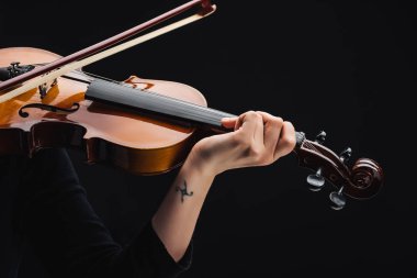 cropped view of woman with tattoo playing cello with bow isolated on black clipart