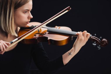 Genç dövmeli kadın siyah üzerinde yay ile çello oynuyor