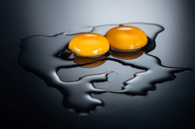 raw chicken yolks and proteins on black background clipart