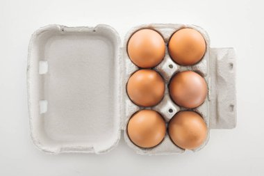 top view of raw brown chicken eggs in carton box on white background clipart