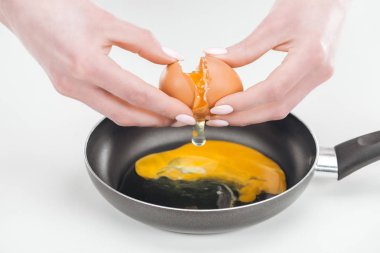 Beyaz arka planda Pan yumurta omlet hazırlarken tavuk yumurtası smashing kadın kısmi görünümü