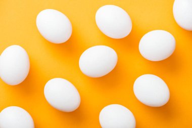 parlak turuncu arka planda tüm beyaz taze tavuk yumurtaları üst görünümü 
