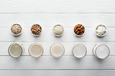 kase malzemeler ile beyaz ahşap yüzey üzerinde Hindistan cevizi, nohut, yulaf, pirinç ve badem sütü ile gözlük üst görünümü