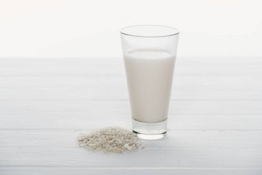 rice milk in glass near rice grains on wooden table isolated on white clipart