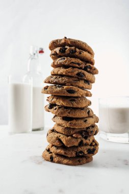 selective focus of chocolate cookies near bottle and glasses with milk on marble table clipart