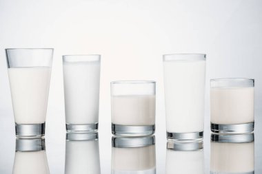 row of glasses with organic fresh vegan milk on grey background with reflection clipart