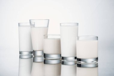 row of glasses with fresh alternative milk on grey background with reflection clipart
