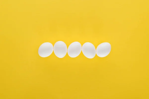 Sarı Arka Planda Satırda Beş Beyaz Tavuk Yumurtası — Stok fotoğraf