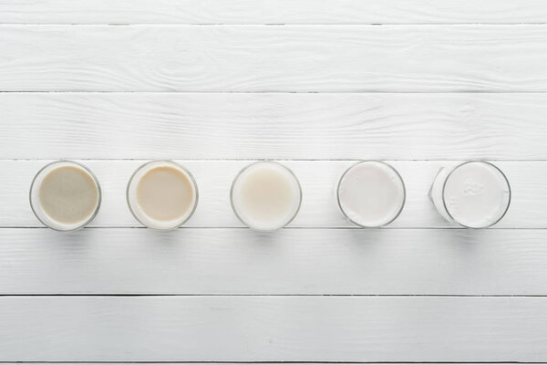 top view of different types of milk on white wooden surface
