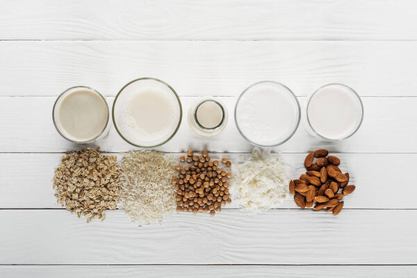 top view of glasses and bottle with coconut, chickpea, oat, rice and almond milk near ingredients 