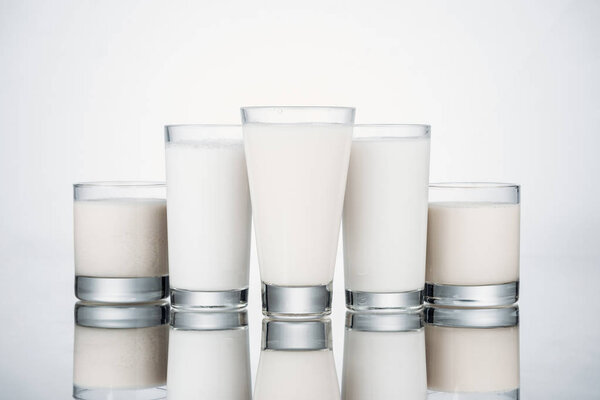 glasses with organic alternative milk on grey background with reflection
