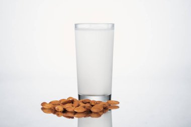 almond vegan milk in glass nuts on grey background clipart
