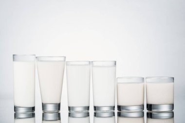 row of glasses with organic vegan milk on grey background clipart