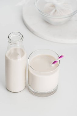 selective focus of rice milk in bottle and glass with rice in cheesecloth on background clipart
