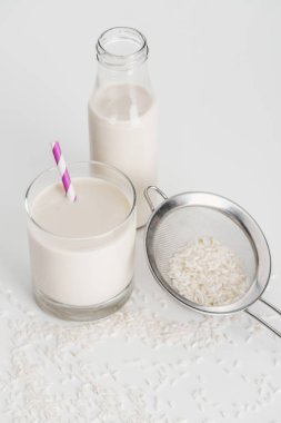 şişe ve cam içinde saman ile pirinç sütü dağınık pirinç ve gri arka planda elek yakın