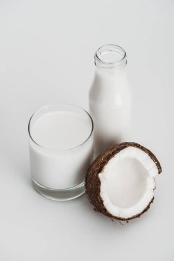 Cam ve şişe yakın Hindistan cevizi yarısı gri arka planda organik Vegan Hindistan cevizi sütü