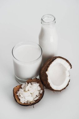Cam ve şişe yakın Hindistan cevizi yarım ve Hindistan cevizi cips gri arka planda organik Vegan Hindistan cevizi sütü