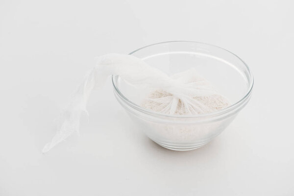 rice in cheesecloth in glass bowl on grey background
