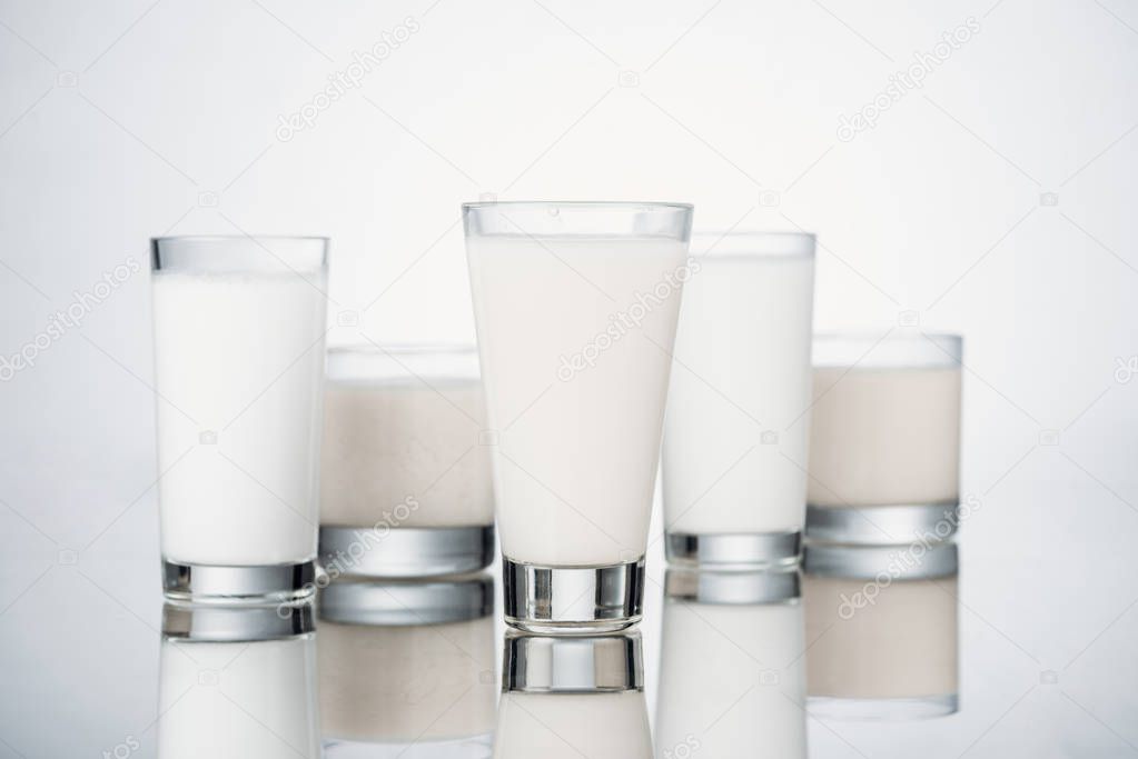 glasses with fresh alternative milk on grey background with reflection